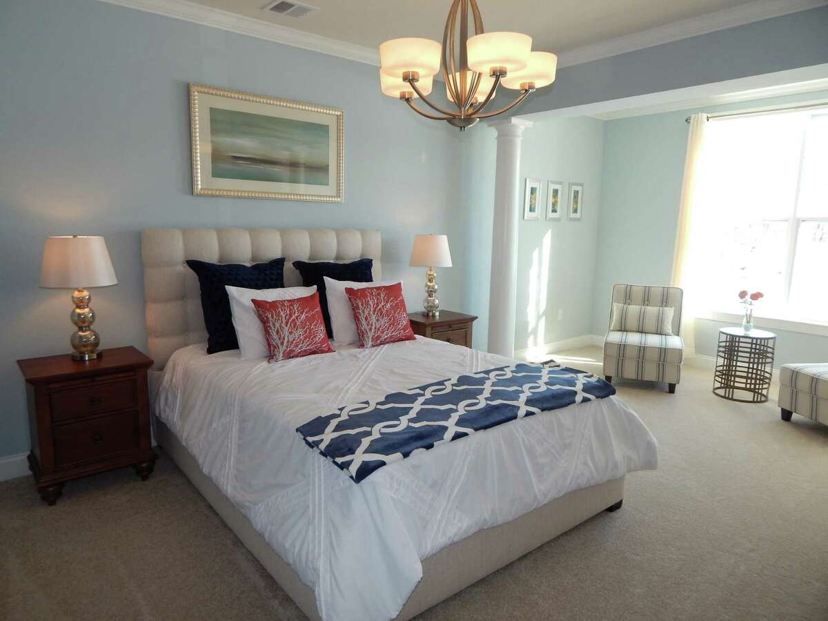 The master bedroom in this Newtown home has a neutral color palette that is paired with different tones of navy, white and coral accents, reminiscent of sand, shells, ocean and sky. It's all part of the coastal look. This photo was provided by PJ & Company Staging and Interior Decorating.