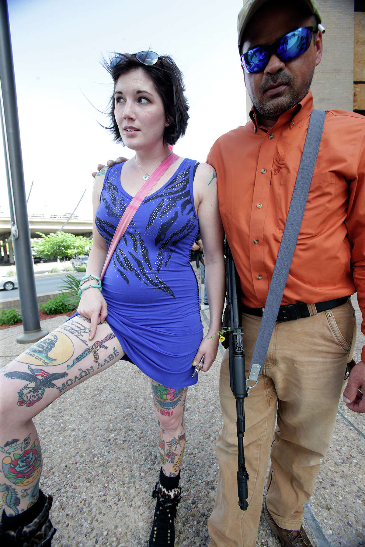 Victoria Montgomery shows a fresh rifle tattoo with friend Ronald Young as Texas Open Carry demonstrators gather on the steps of the Austin Police Department to take issue with Police Chief Art Acevedo's stance on the topic of firearm carrying on May 6, 2015.