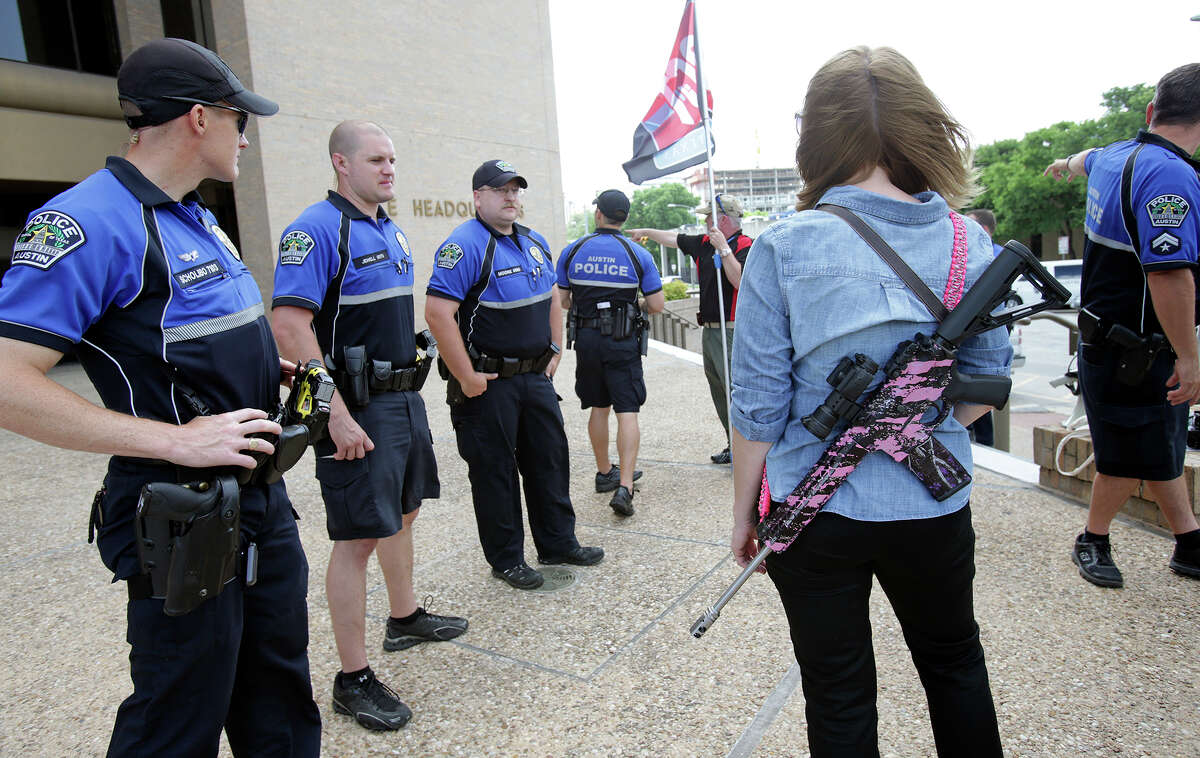 Emily Grisham stands near police officers checking out the scene as Texas Open Carry demonstrators gather on the steps of the Austin Police Department to take issue with Police Chief Art Acevedo's stance on the topic of firearm carrying on May 6, 2015.