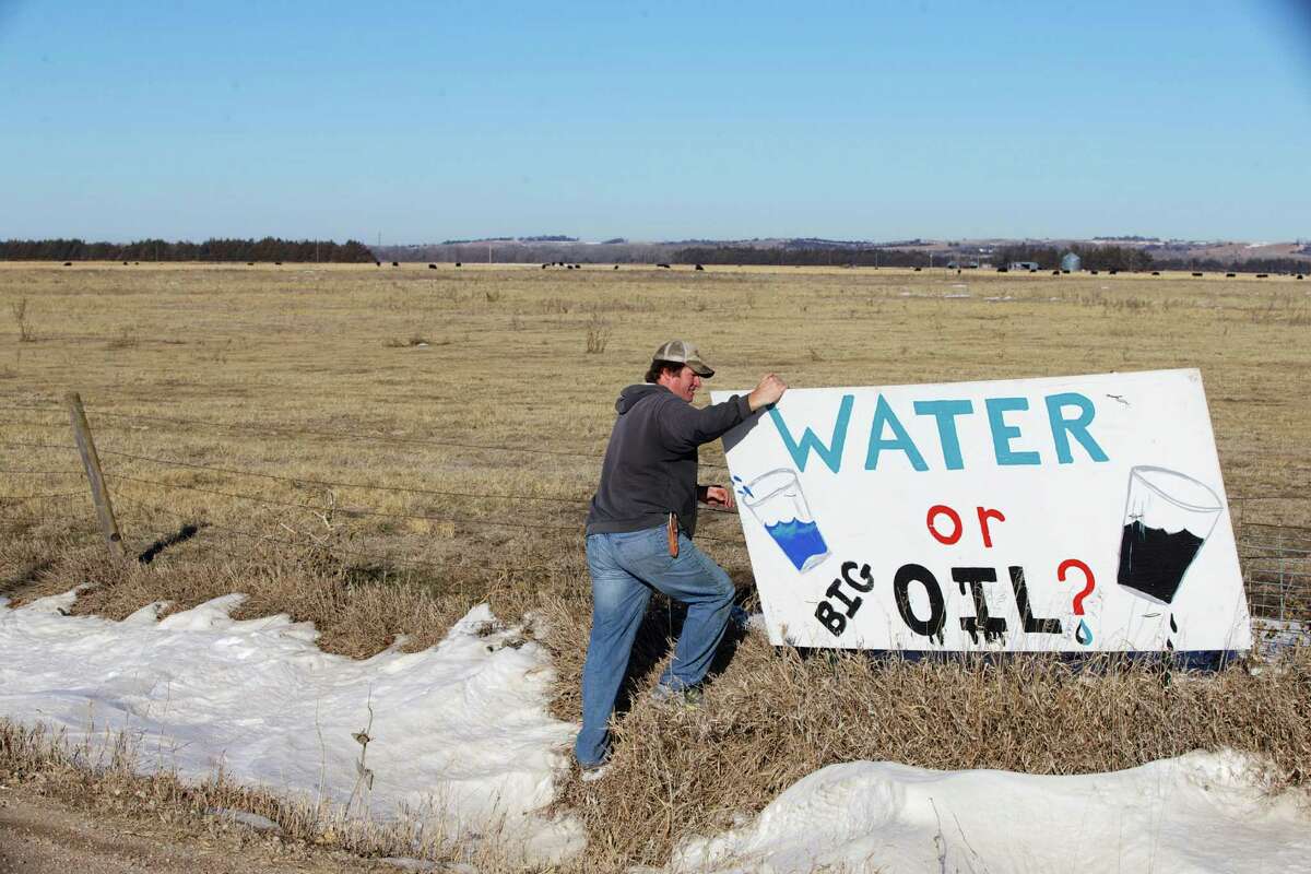 Land owner Jim Tarnick of Fullerton, Neb., who opposes the Keystone XL pipeline, hangs on to an anti-Keystone XL pipeline sign at the site where the planned pipeline is to go through his land, Friday, Jan. 16, 2015. The White House has threatened to veto several bills the Republicans have prioritized, including approving construction of the Keystone XL oil pipeline.