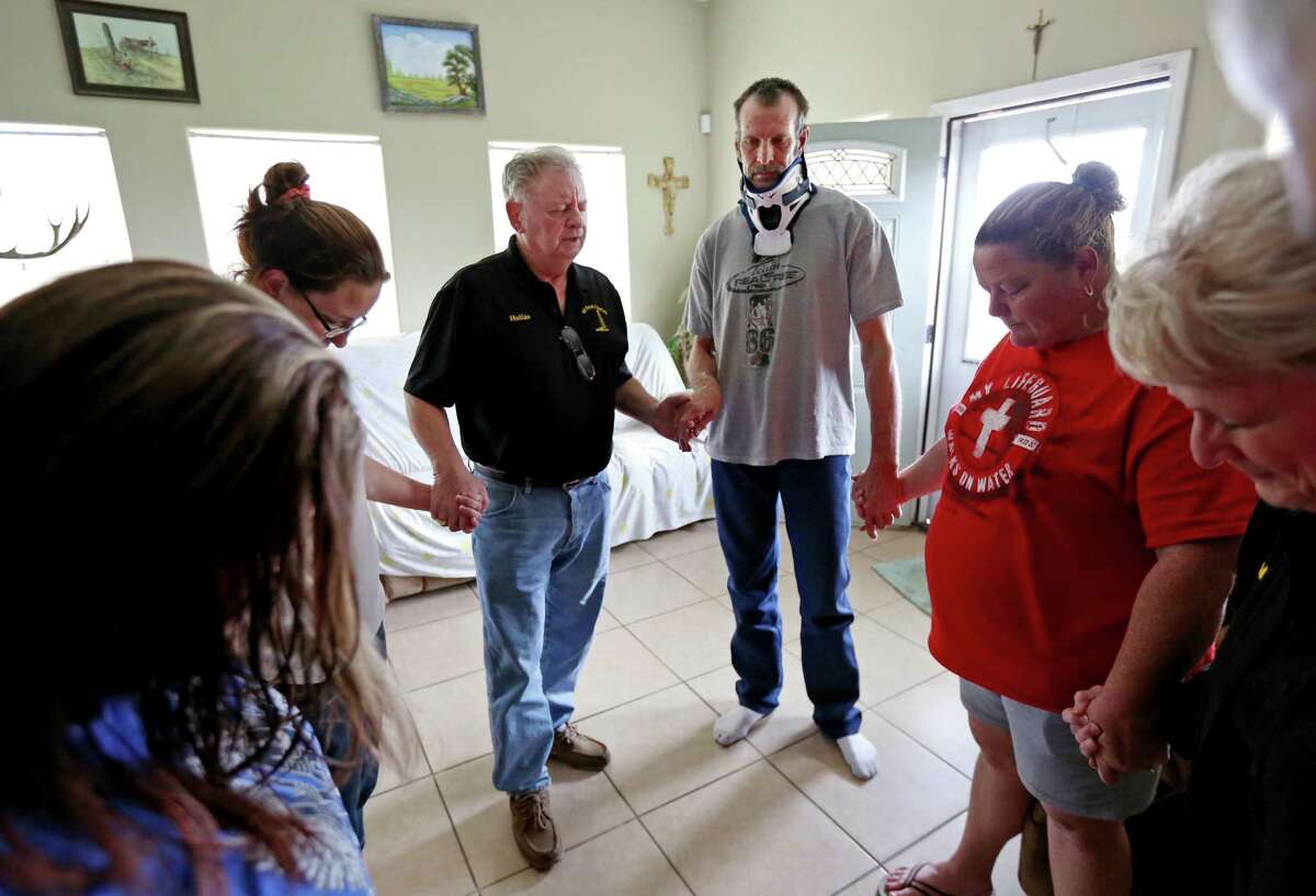 Hollas Hoffman, in black shirt, co-founder of Oil Patch Chaplains, prays with John Salmon, a truck driver with Wrangler Trucking, and his wife Rebecca Salmon, in red shirt, and others in Gonzales.