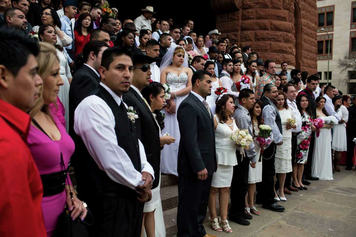 Dozens of couples wait to be wed during one of the free mass wedding ceremonies held annually on the steps of the Bexar County Courthouse on Valentine's Day, Saturday, February 14, 2015.