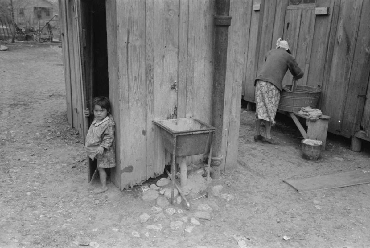 This photo labeled "Mexican girl coming from privy, woman washing clothes, San Antonio" in March 1939 by Russell Lee shows poor living conditions in the 30s in San Antonio. Farm Security Administration - Office of War Information Photograph Collection.