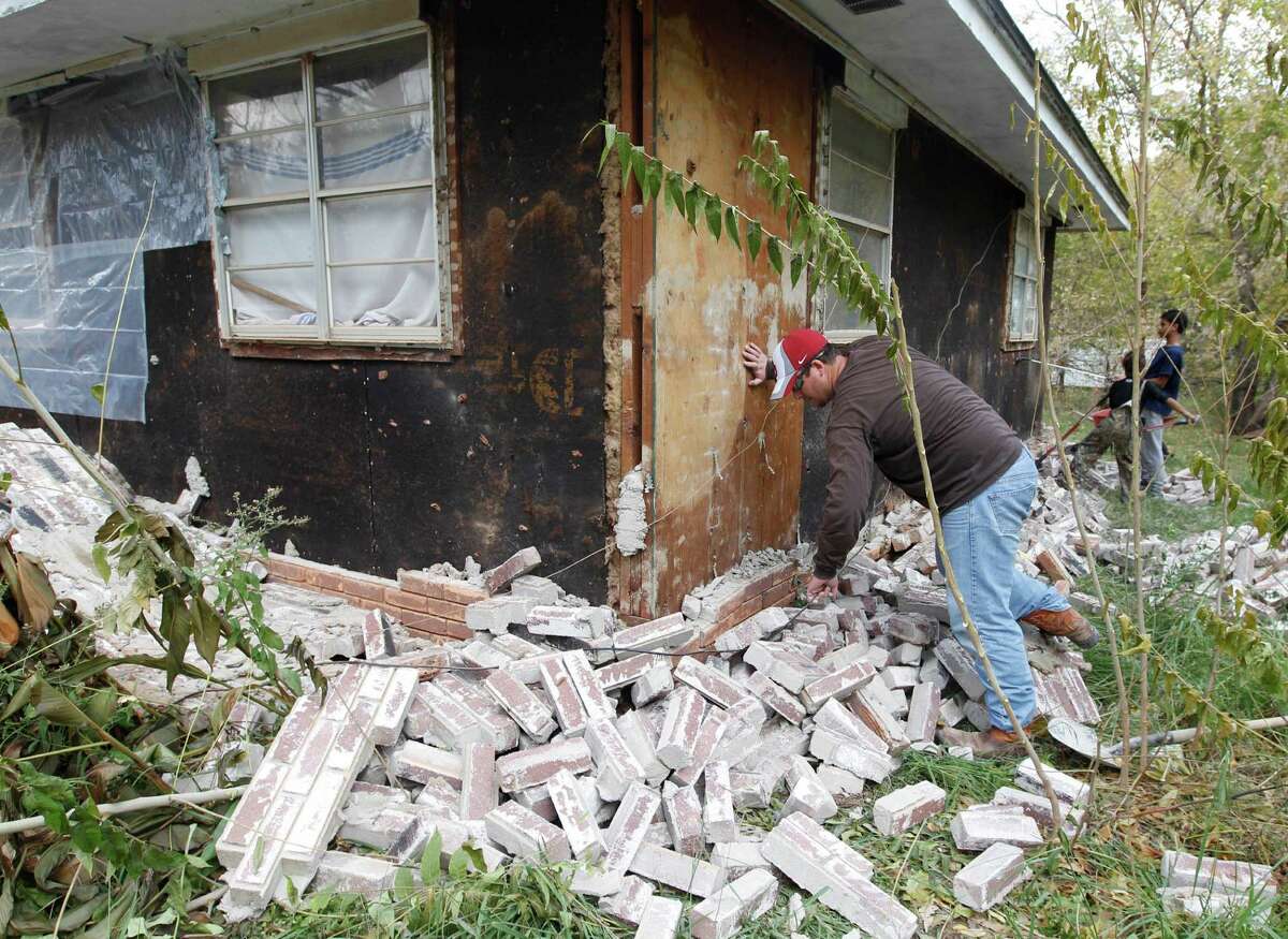 Chad Devereaux examines bricks that fell from three sides of his in-laws’ home in Sparks, Okla., after two earthquakes hit.