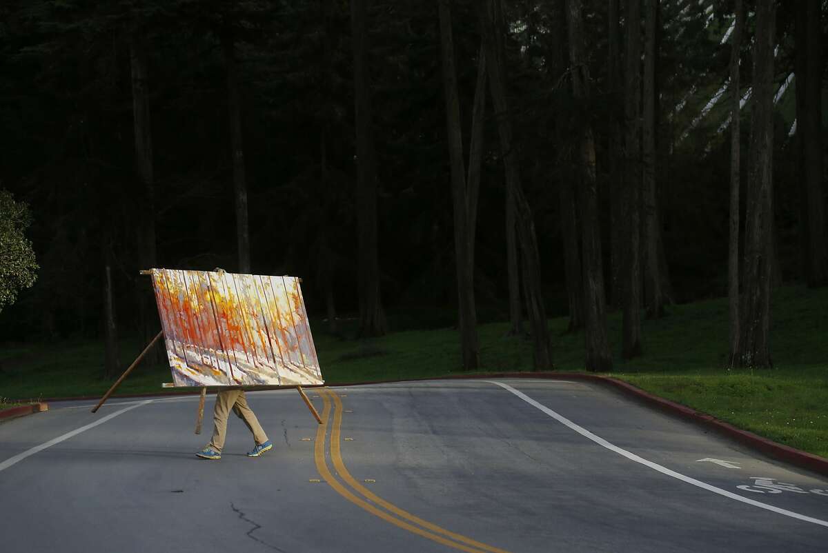 At the end of a long day, Nicholas Coley carries his nearly complete painting to his truck in the Presidio on Wednesday Feb. 11, 2015 in San Francisco, Calif.