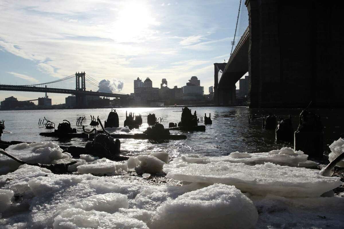 Ice forms under the Brooklyn Bridge, right, on the Manhattan side of the East River in New York on Monday, Feb. 16, 2015. Temperatures in the city were in the single digits on Monday morning. The Manhattan Bridge is at background left. (AP Photo/Peter Morgan) ORG XMIT: NYPM103