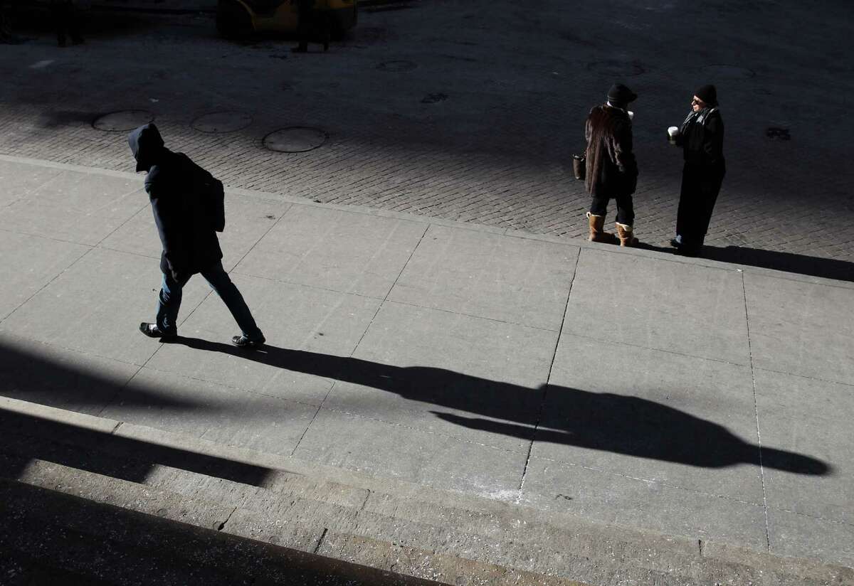 People dressed for cold weather pause and walk on Wall Street in New York on Monday, Feb. 16, 2015. Temperatures were in the single digits in the city on Monday morning. (AP Photo/Peter Morgan) ORG XMIT: NYPM104