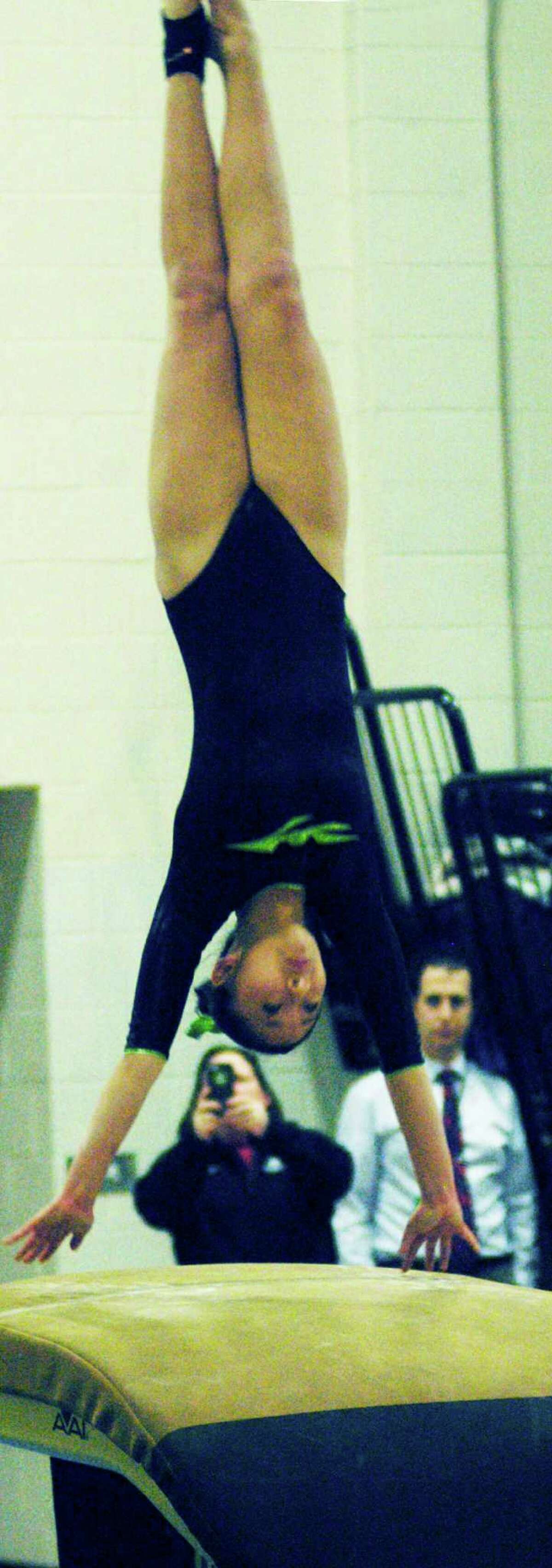 The Green Wave's Angela Lian offers a strong vault for New Miford High School gymnastics as Green Wave field hockey coach Dawn Hough captures the moment and NMHS assistant principal Mark Balanda looks on during the South-West Conference championship meet, Feb. 12, 2015 at NMHS.
