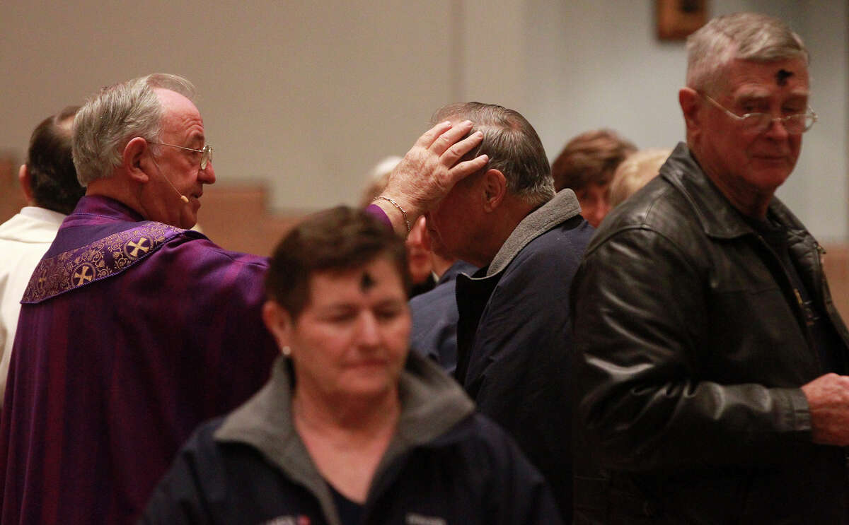 Faithful receive ashes from Monsignor Michael O'Gorman (left) on Ash Wednesday February 18, 2015 at Saint Mark the Evangelist Church in San Antonio.