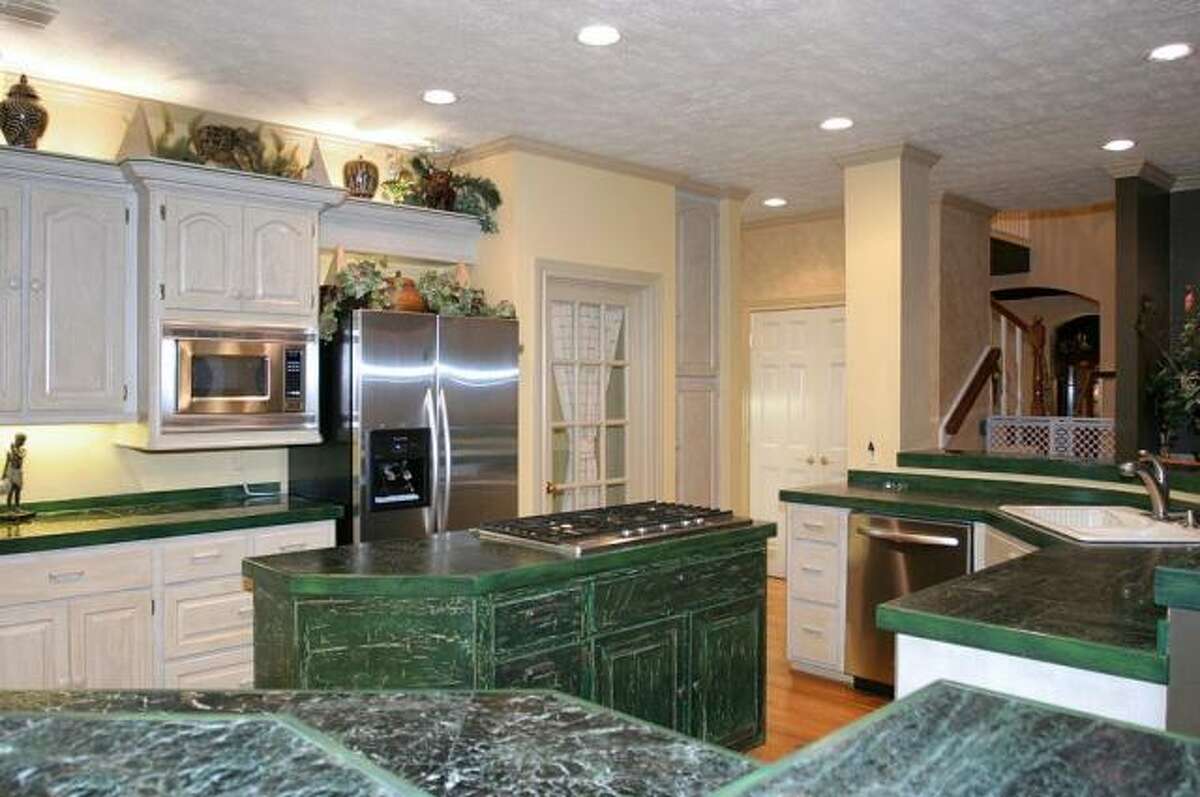 Kathy Anderson replaced these green wraparound cabinets with one big granite island. She also replaced the white cabinets with new custom cabinetry.