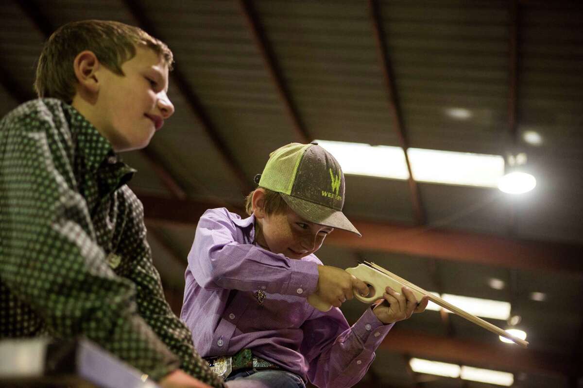 Trey Harbour, 9, watches his friend Costin Allison, 10, shoot rubber bands at Allison's father at the San Antonio Stock Show and Rodeo in San Antonio, TX on Wednesday, February 18, 2015.