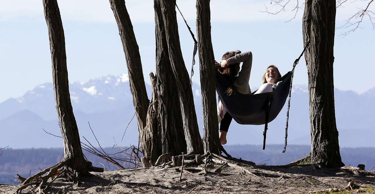 HAMMOCK RENDEZVOUS: Taylor Wilkinson and Karissa Courtney, both Seattle Pacific University students, share a hammock overlooking the Puget Sound and the Olympic Mountains in Seattle. Temperatures hit record highs a day earlier in parts of Washington and Oregon as one of the mildest winters continues in the Northwest.
