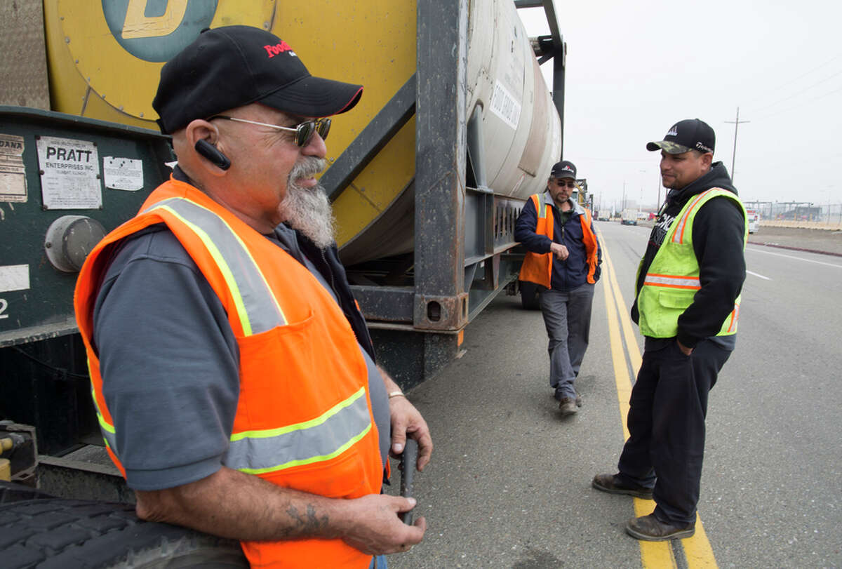 Stockton truckers Jose Gutierrez (left), Jose Lopez and Fran cisco Sanchez wait to drop off their loads at Oakland’s port.