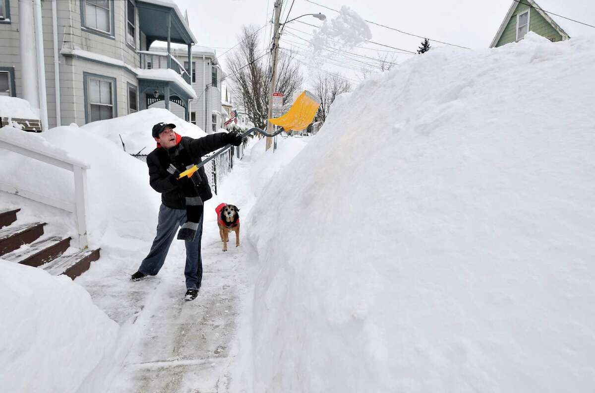FILE - In this Feb. 10, 2015 file photo, Lee Anderson adds to the pile of snow beside the sidewalk in front of his house in Somerville, Mass., as his dog Ace watches. It may be hard to believe for a country thatâs shivering from Maine to Miami, but 2014 has gotten off to a rather toasty start. Meteorologists said that last month was the second warmest January on record globally, behind 2007, with temperatures 1.4 degrees above 20th century average. The National Oceanic and Atmospheric Administration calculated that the United States in January was 2.9 degrees warmer than normal, making it the 24th warmest January since 1880. (AP Photo/Josh Reynolds, File)