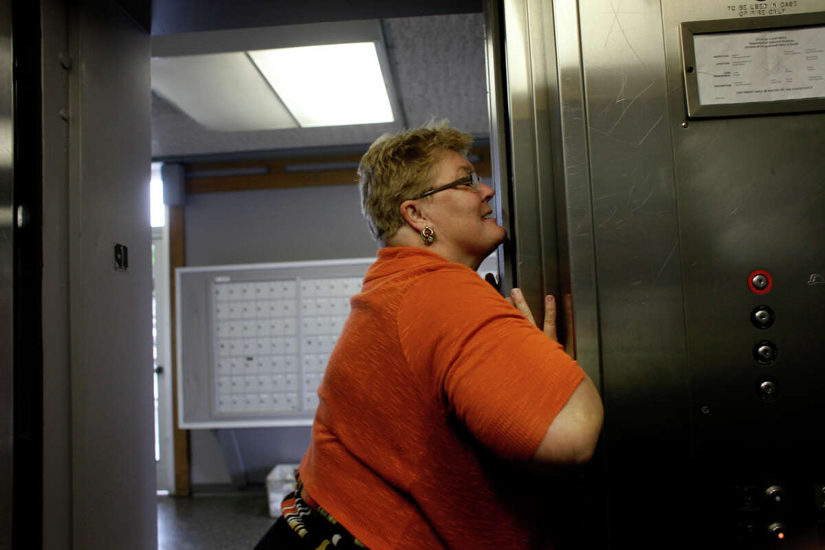 Richmond Housing Authority official Debra Holter pushes and squeezes the elevator doors to get it to work in the Hacienda public housing complex in February 2014.