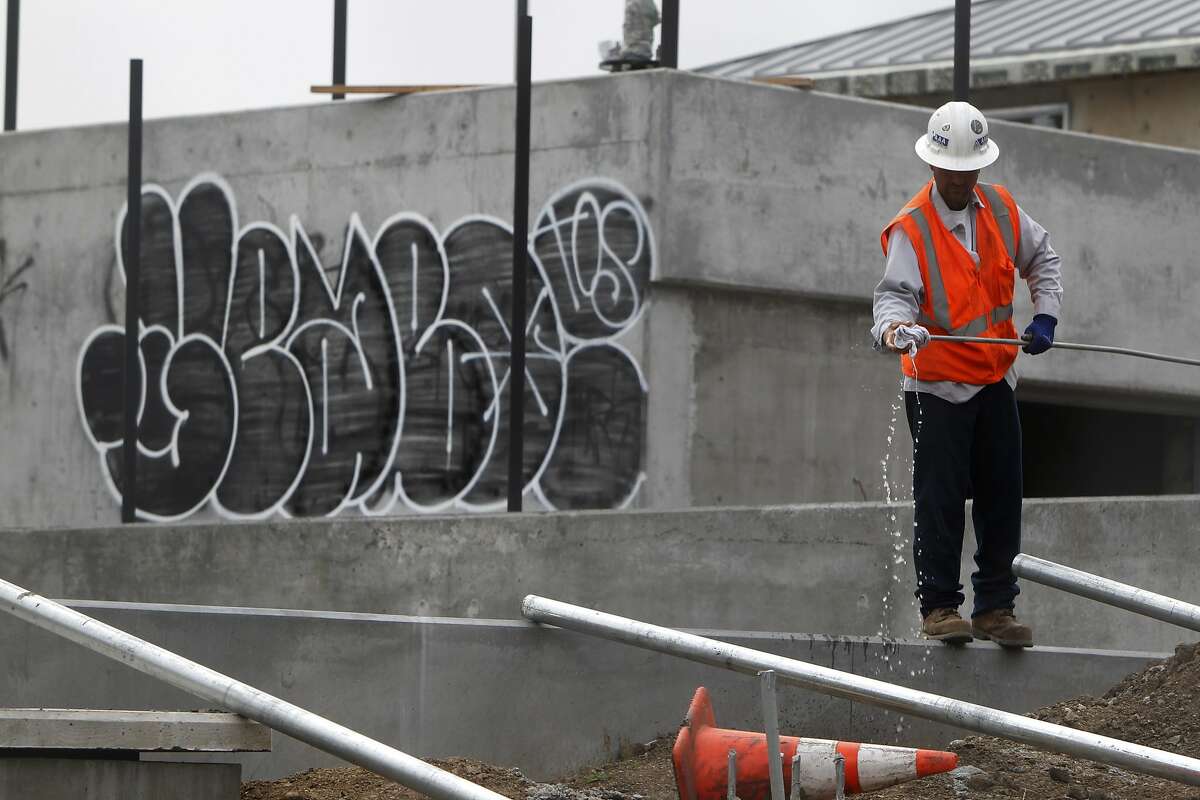A man works near a graffitied wall on the site of new construction at Dolores Park in the Mission District of San Francisco, Calif. Friday, February 20, 2015 after vandals caused $100,00 in damage over the weekend, setting back the date for re-opening indefinitely.