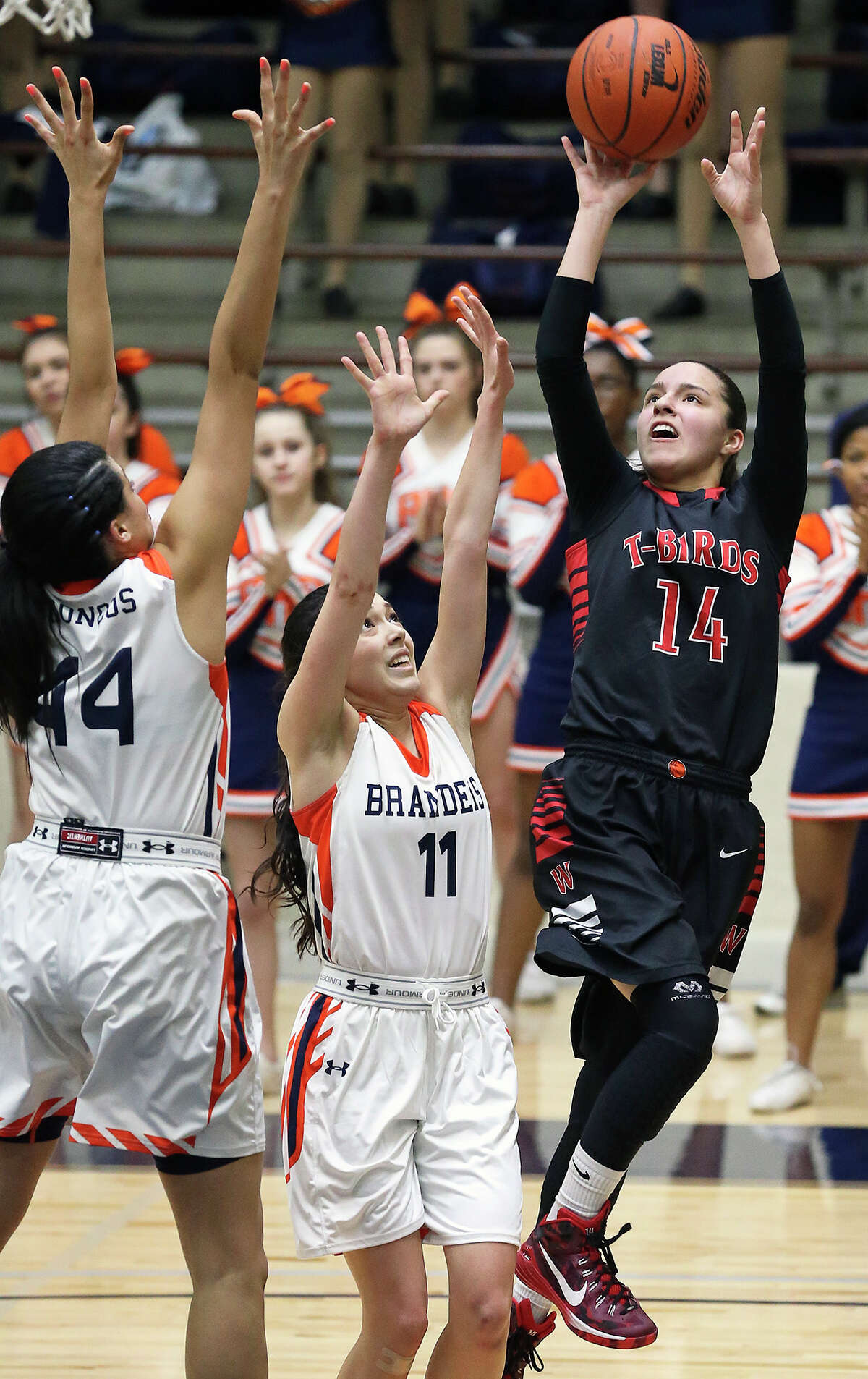 T-Bird guard Amber Ramirez pops up for a baseline jumper against Morgan Williams (44) and Kyana Alvarez as Brandeis plays Wagner in second round 6A girls basketball playoff action at the Alamo Convocation Center on February 20, 2015