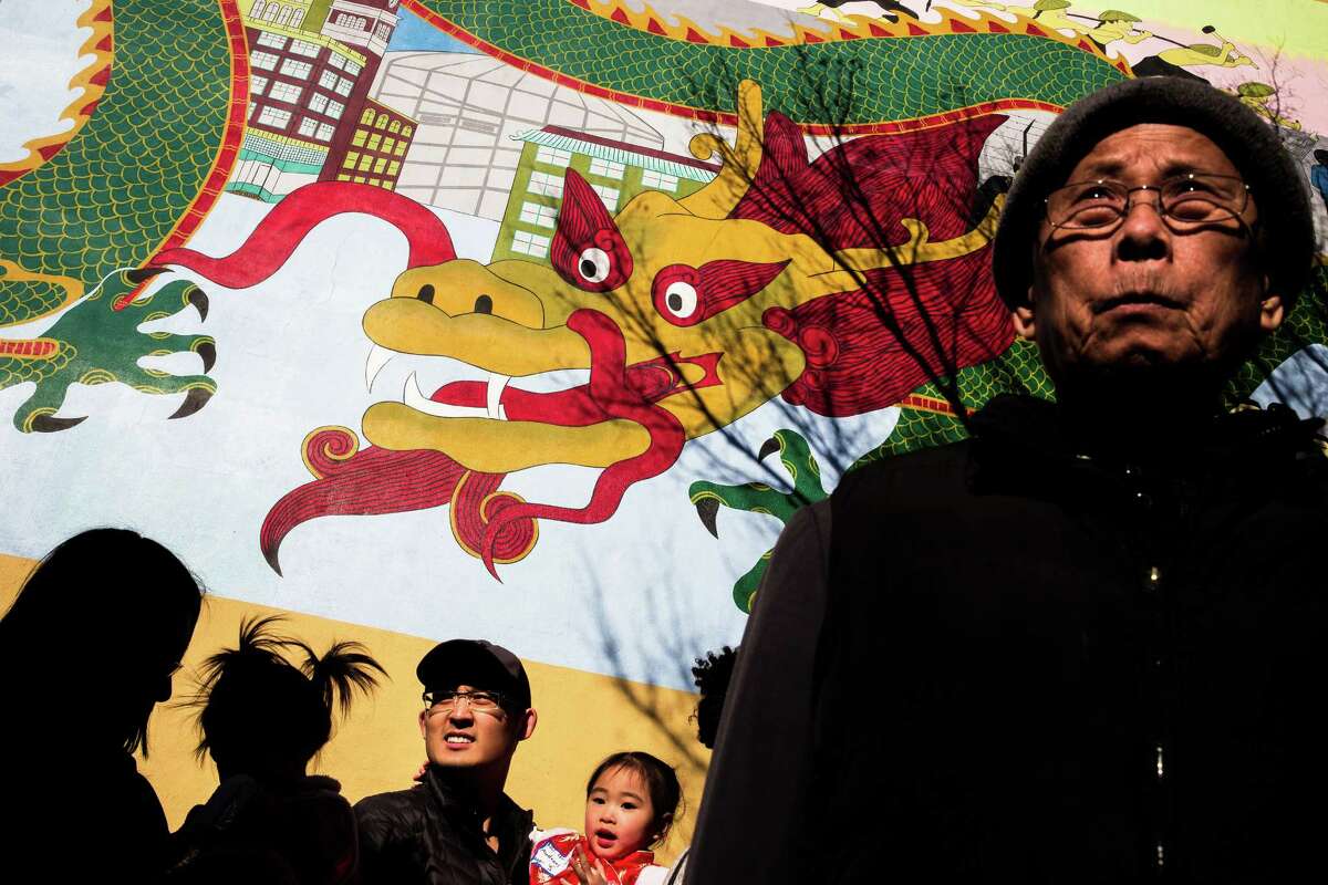 Families and dressed up children await a costume contest under a large dragon mural during the annual Lunar New Year Celebration Saturday, February 21, 2015, within Chinatown in Seattle, Washington. The day-long celebration includes traditional dragon and lion dances, Japanese Taiko Drumming, martial arts, delicious foods and crafting.