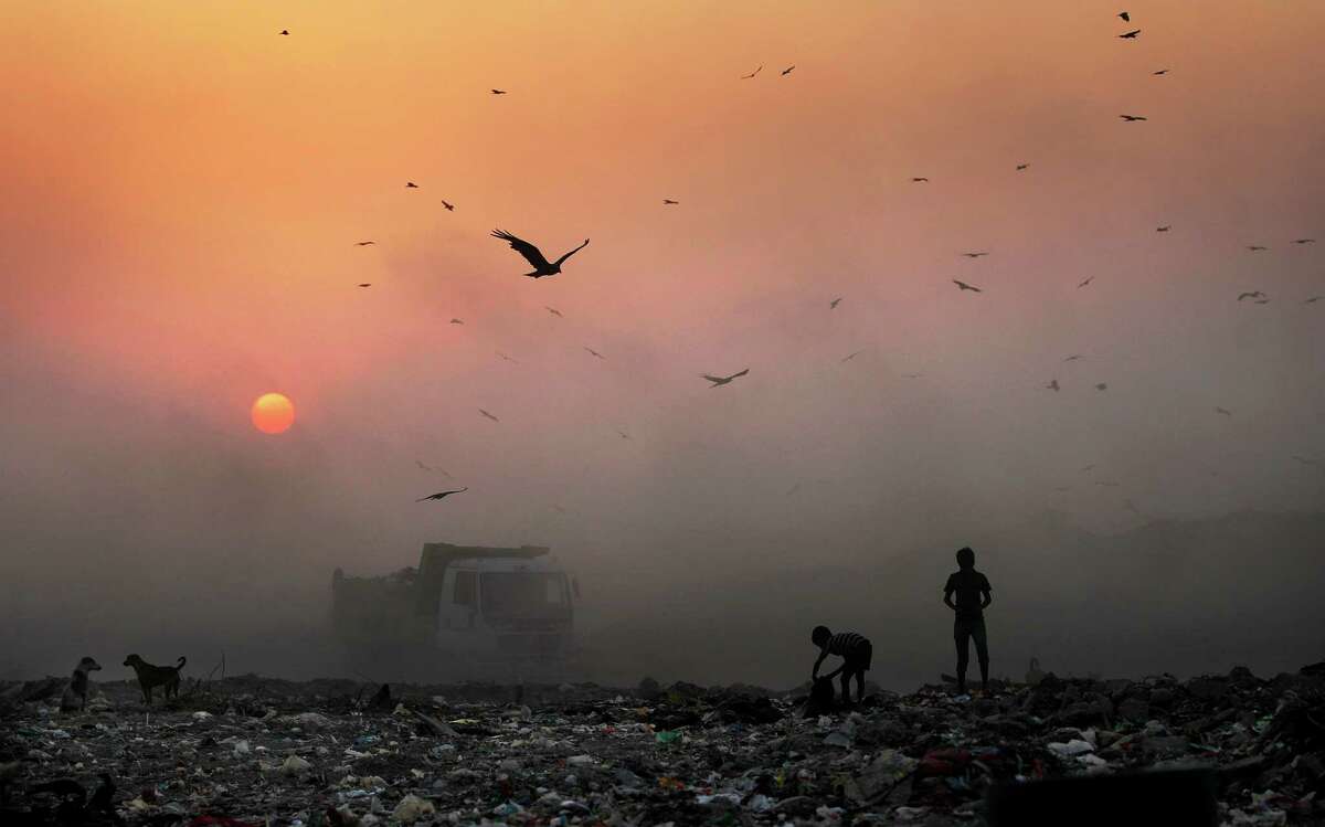FILE- In this Oct. 17, 2014, file photo, a thick blanket of smoke is seen against the setting sun as young ragpickers search for reusable material at a garbage dump in New Delhi, India. Indiaâs filthy air is cutting 660 million lives short by about three years, while nearly all of the countryâs 1.2 billion citizens are breathing in harmful pollution levels, according to research published Saturday, Feb. 21. While New Delhi last year earned the dubious title of being the worldâs most polluted city, the problem extends nationwide, with 13 Indian cities now on the World Health Organizationâs list of the 20 most polluted. (AP Photo/Altaf Qadri, File)