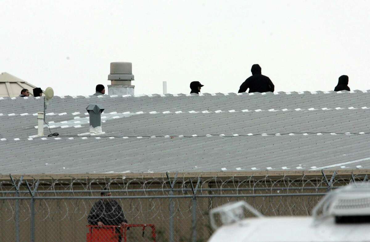 SPECIAL TO THE EXPRESS NEWS RAYMONDVILLE, Tx-Correctional guards at the Willacy County Correctional Center in Raymondville, Texas peer from the roof top Saturday Feb.21, 2015. Ed Ross, a spokesman for the U.S. Bureau of Prisons, said the inmates who had taken control are "now compliant" but that negotiations were ongoing Saturday in an effort for staff to "regain complete control" of Willacy County Correctional Center.Photo by Delcia Lopez