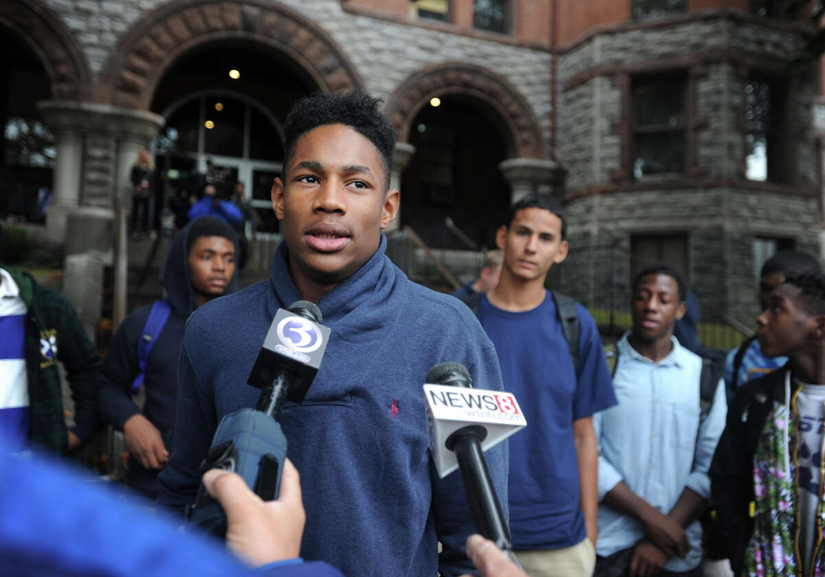 Surrounded by his teammates, Harding High School point guard T.J. Killings addresses the media outside Superior Court in Bridgeport, Conn. following the arraignment of coach Charles Clemons, Jr. on the charge of risk of injury to a minor on Wednesday, October 1, 2014. Killings called Clemons a father figure, and said the team was a like a family.