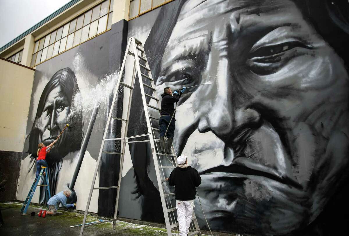 Volunteers scrub and spray off a vandal's paint after Native American artist Andrew Morrison's murals at Seattle's Wilson-Pacific school building were desecrated. On Wednesday, February 25, 2015, more than a dozen volunteers removed the paint from the artwork.