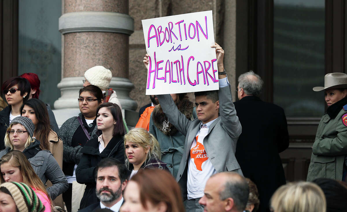 Cold air keeps participants huddled as college students and abortion rights activists gather on the steps of the State Capitol to demonstrate for their cause on February 26, 2015.