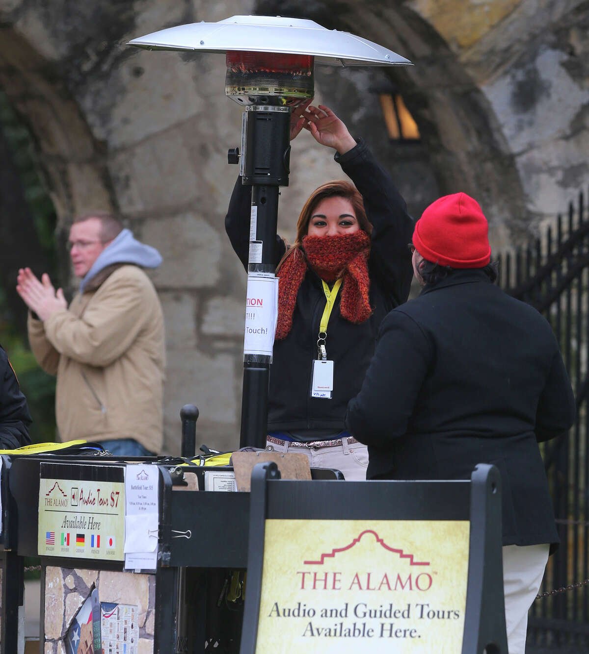 Idalis Salinas (center) warms her hands under a portable heater Friday February 27, 2015 in front of the Alamo in downtown San Antonio. Temperatures in the area have been in the 30 degree range and might make it into the 40s by this afternoon.