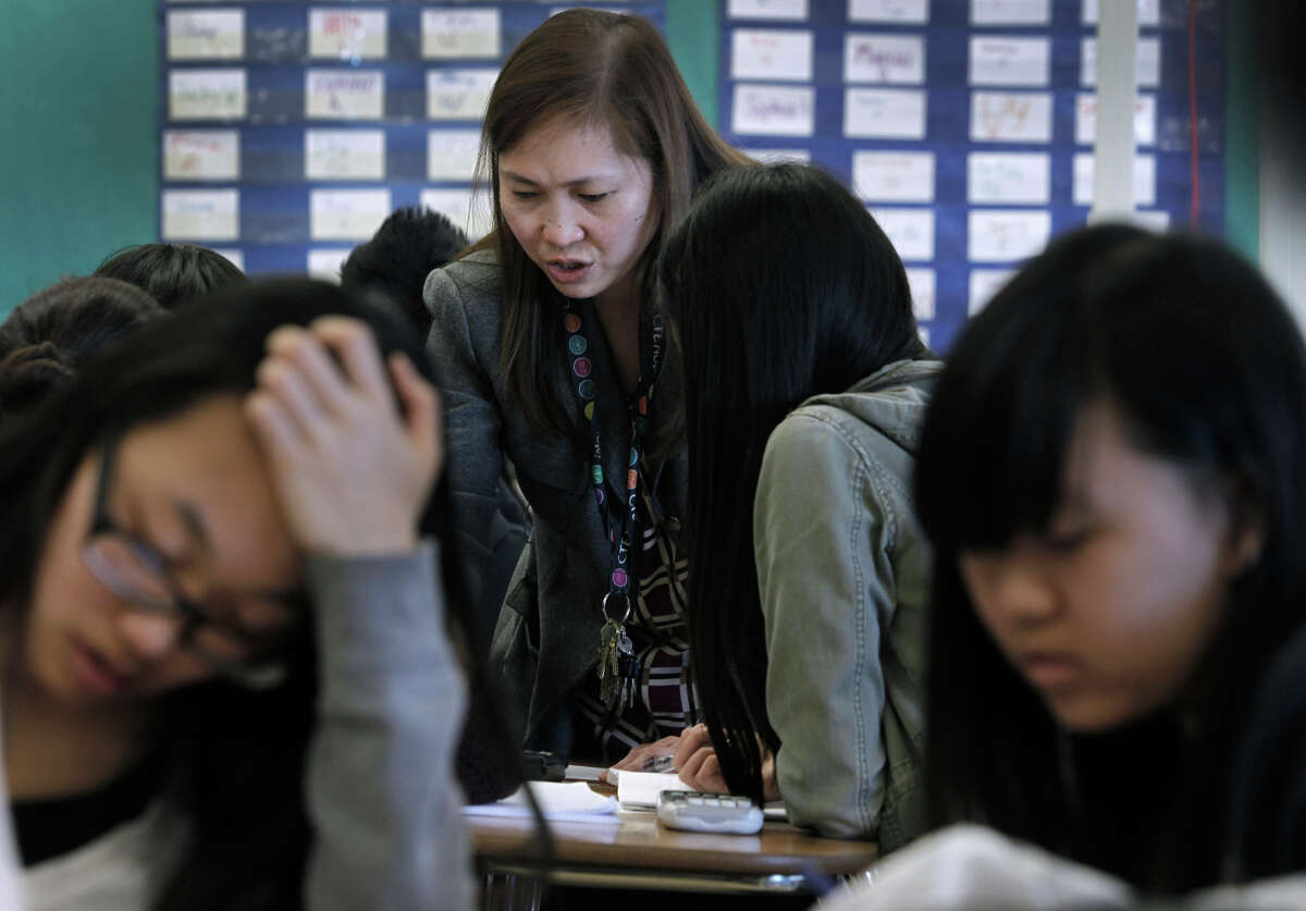 Teacher Mary Ann Castro helps students in Advanced Placement Calculus at Burton High School in S.F. Parents are not happy with the new sequence of math courses which delays Algebra 1 until ninth grade.