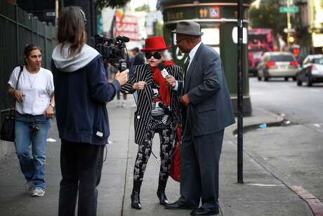Performing as the host of “The Mister Geoffrey Show,” Geoffrey Grier interviews Deborah Marinoff in San Francisco’s Tenderloin neighborhood to get a better understanding of the residents in the area.