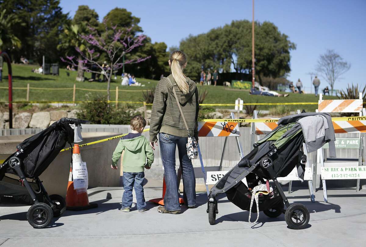 Theo Wolens (3) and his mother, Katie Lamont, look into the empty sandbox in the children's playground at Dolores Park in San Francisco on Sunday, March 1, 2015. The sandbox was found full of broken glass bottles on Friday, forcing maintenance staff to replace all of its sand.