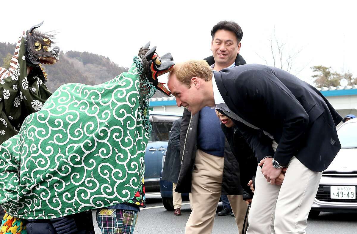 THERE GO A FEW MORE ROYAL FOLLICLES: In Ishinomaki, Japan, a Lion Dancer greets Prince William by gnawing on his head during the Shishimai Ceremony.