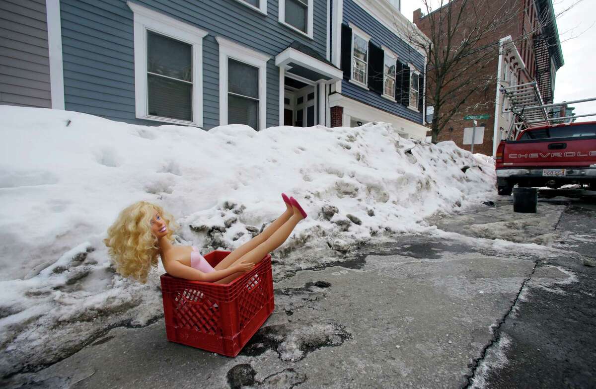In this Feb. 23, 2015 photo, a fashion doll in a milk crate saves a parking space on a residential street in South Boston. Officials typically turn a blind eye to the lawn chairs, orange cones and assorted bric-a-brac Bostonians use to reserve a parking space after clearing it of snow. That ends Monday, March 2, 2015, with an order from City Hall to remove space savers, reigniting the ugly parking wars that have pitted neighbor against neighbor. (AP Photo/Elise Amendola) ORG XMIT: MAEA103