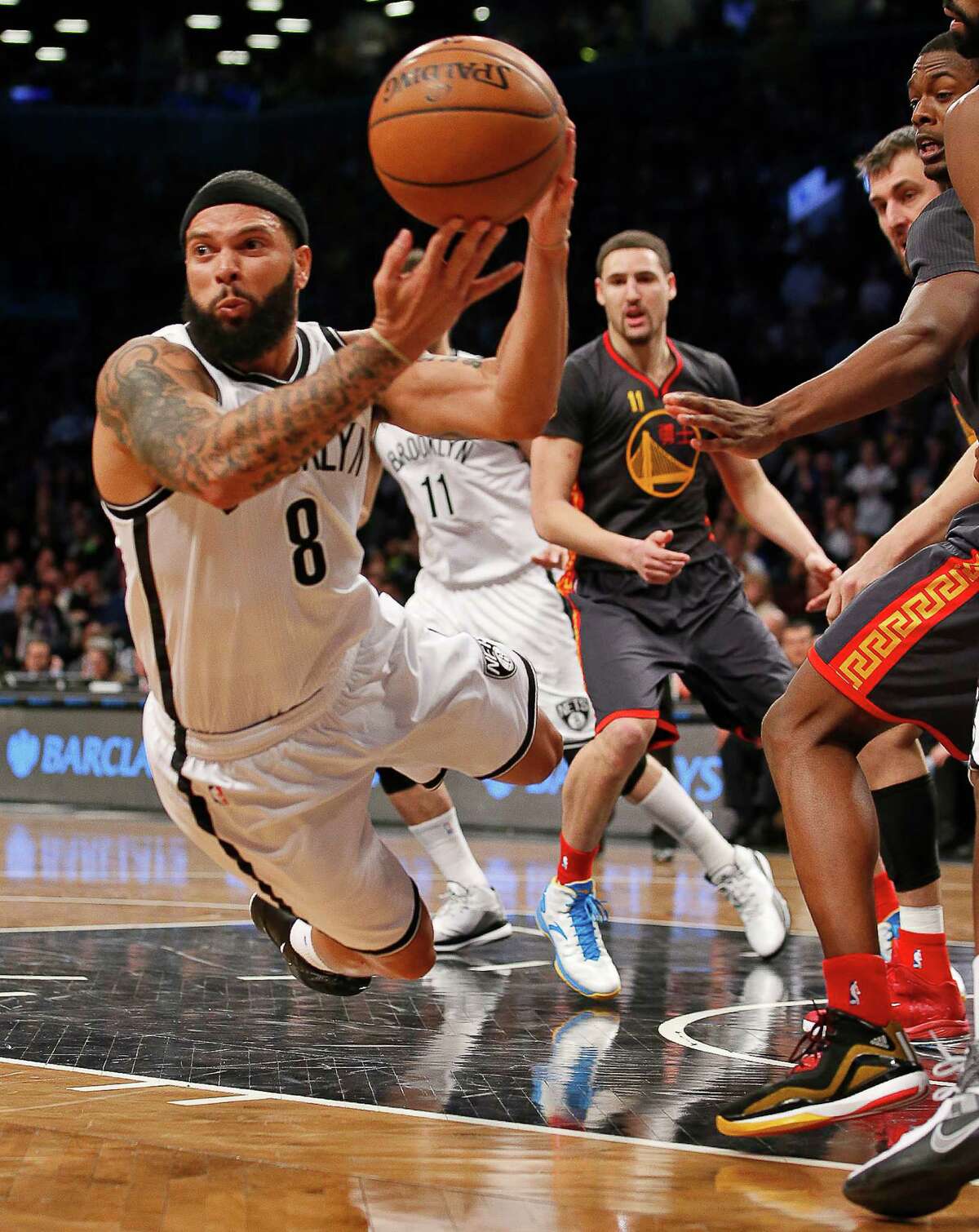 Brooklyn Nets guard Deron Williams (8) looks to pass to the perimeter as he falls to the floor in the second half of an NBA basketball game against the Golden State Warriors at the Barclays Center, Monday, March 2, 2015, in New York. Williams had 22 points as the Nets defeated the Warriors 110-108. (AP Photo/Kathy Willens)