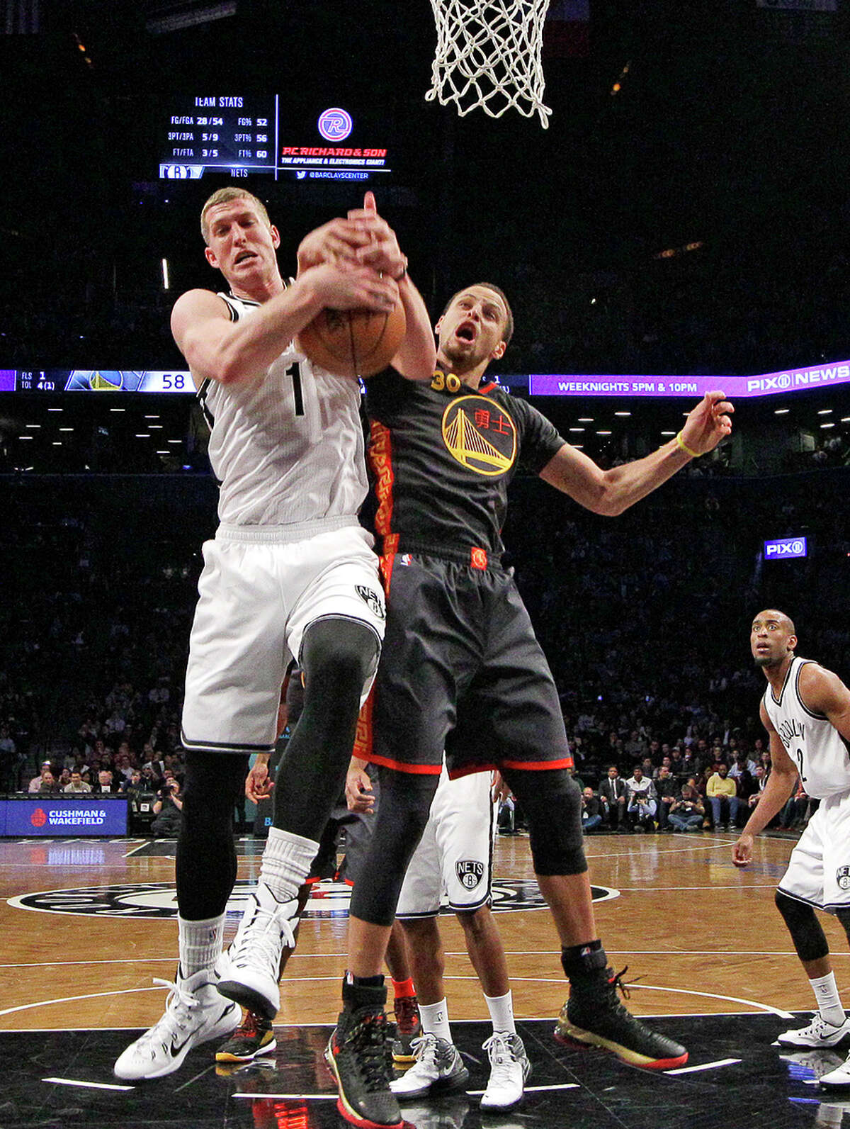 Stephen Curry takes a shot at stripping a rebound from Brooklyn center Mason Plumlee during the first half.