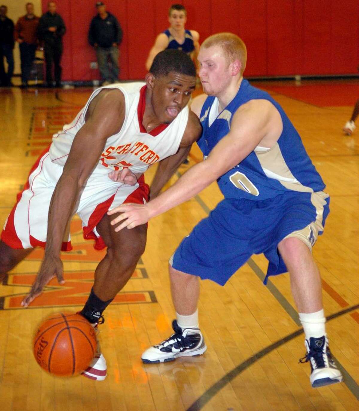 Stratford's #35 Brandon Sherrod, left, takes the ball around Newtown's #50 George Zaruba, during SWC Championship action in Monroe on Thursday March 04, 2010. Stratford went on to win 53-41.