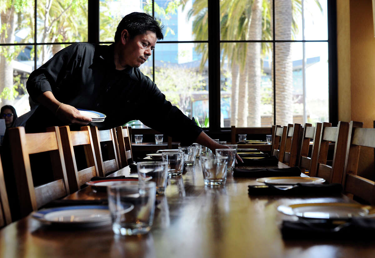 Andres Sanchez sets a table for lunch at Oakland’s Bocanova, which has done away with traditional tipping.