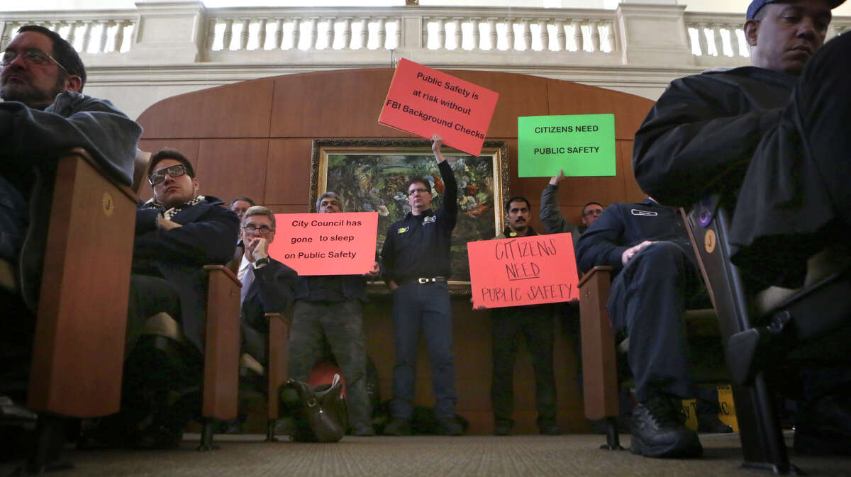 Taxi company employees hold signs at City Hall before the city council votes on changes to the city's vehicle-for-hire ordinance. Thursday, March 5, 2015.