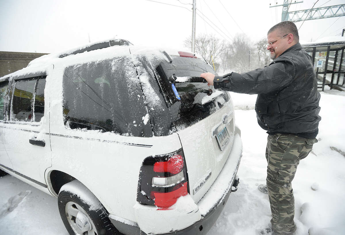 Andrew Vincent, of Shelton, scrapes the ice and snow from his car windows at the Stratford Train Station in Stratford, Conn. on Thursday, March 5, 2015.