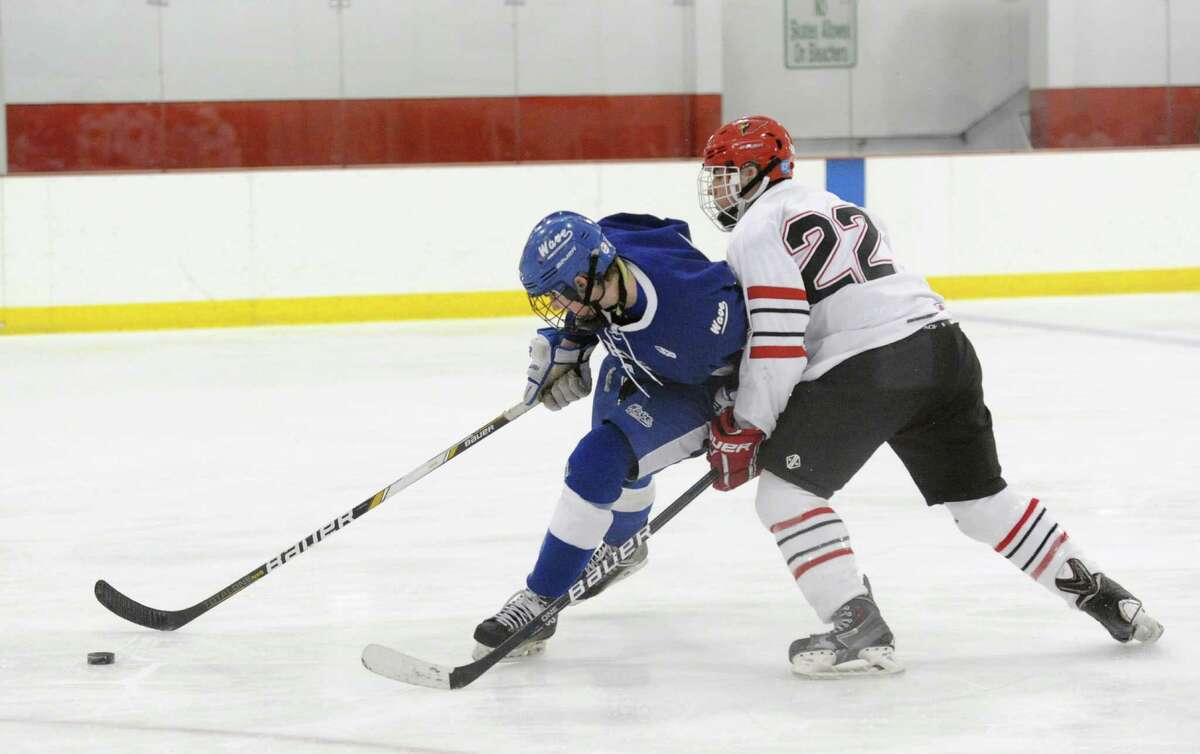 At left, Darien's Brendan Cassidy goes for a loose puck against Cal McKinney, of Greenwich, during the game between Greenwich High School and Darien High School on Feb. 3. The game ended in a 3-3 tie. Greenwich and Darien meet again Saturday in the FCIAC tournament finals.