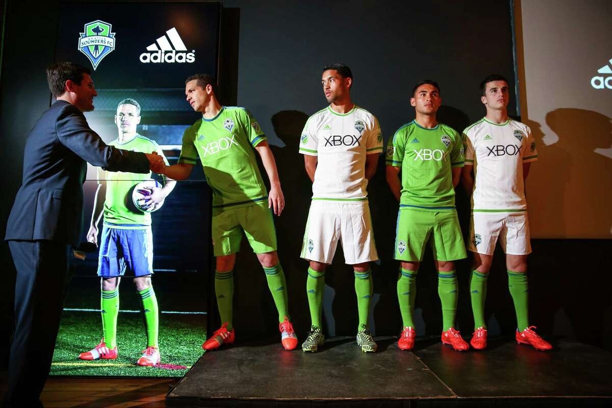 Seattle Sounders players, from left, Osvaldo Alonso , Lamar Neagle, Cristian Roldan, and Aaron Kovar show the new Seattle Sounders uniforms as they are greeted by play-by-play announcer Ross Fletcher during an unveiling at "THE NINETY," the Sounders' front office and event space in Pioneer Square on Thursday, March 5, 2015.