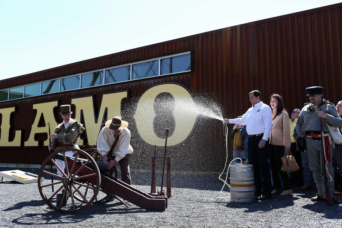 Alamo Beer Co. president Eugene Simor, right, with his wife, Neriza Simor, sprays beer from a keg while Gary Luinstra, far left, and William Manuel work to fire a canon during the Alamo Beer Company Brewery, Beer Hall and Beer Garden Grand Opening on Friday, March 6, 2015.