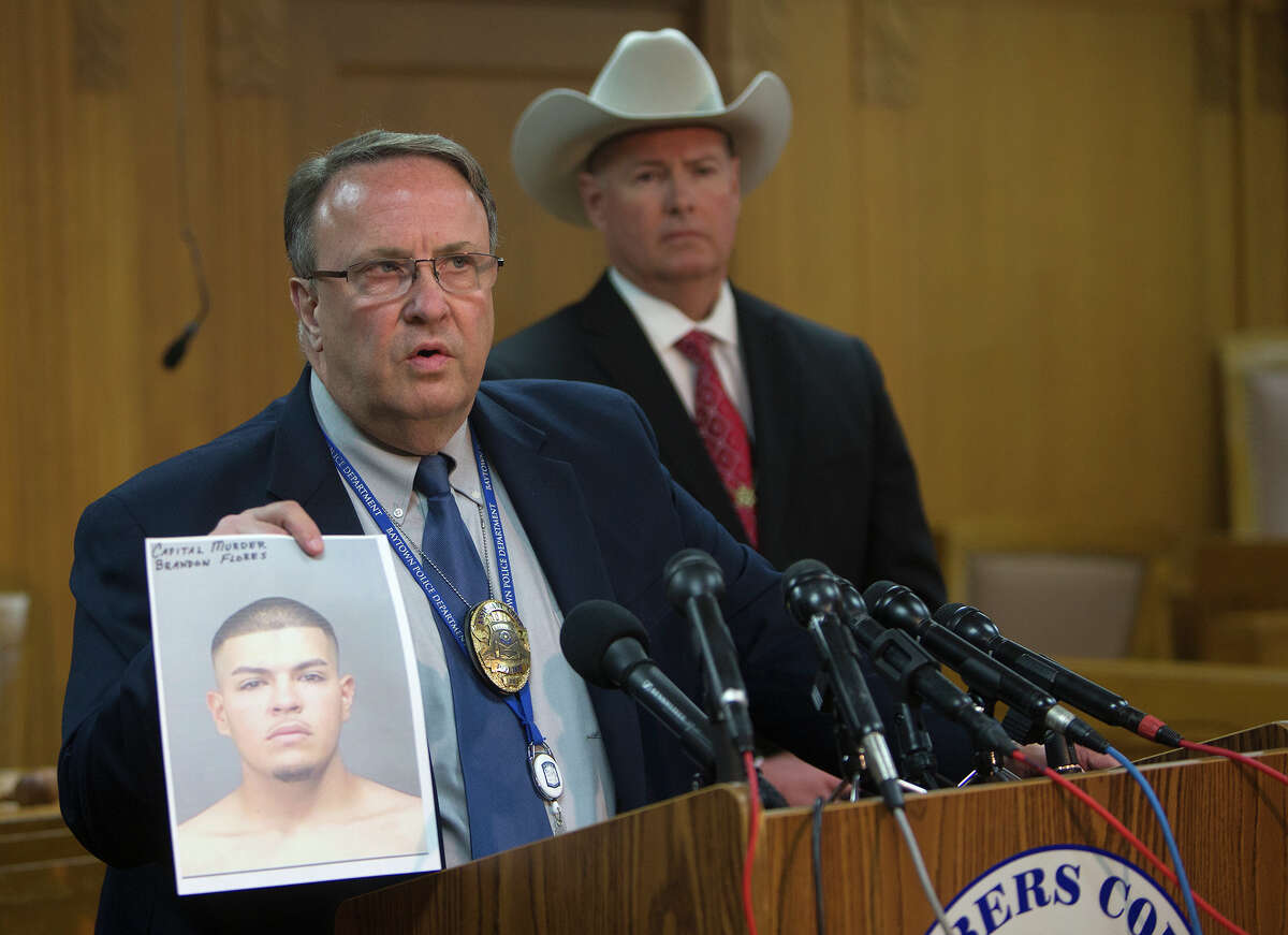 Roger Clifford, a Baytown assistant police chief, holds up a photo of Brandon Flores during a news conference Friday in Anahuac. Flores, 20, a friend﻿ of the victims, has been charged with capital murder.