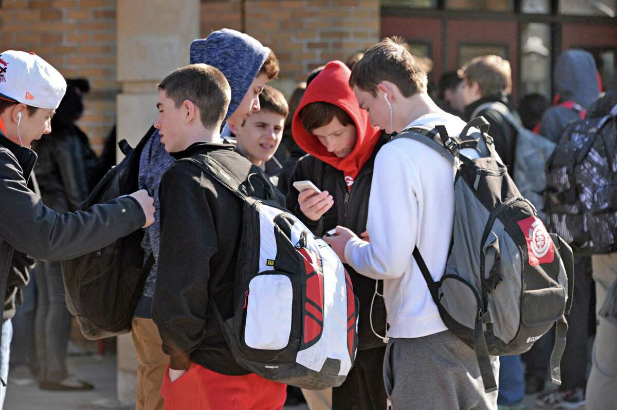 Students use their smart phones while waiting for their bus at Guilderland High School Friday March 6, 2015, in Guilderland Center, NY. (John Carl D'Annibale / Times Union)