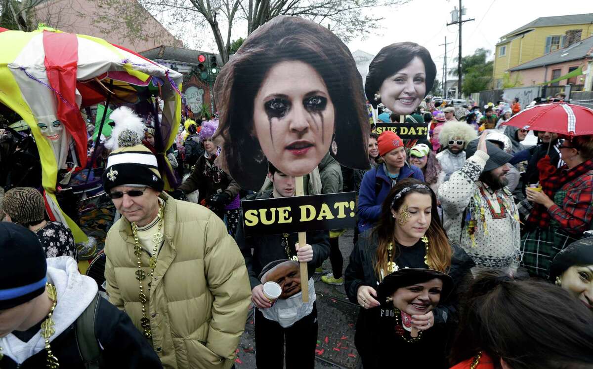 Revelers march with effigies of Rita Benson LeBlanc, granddaughter of New Orleans Saints owner Tom Benson, foreground, and his wife Gayle Benson, background, during one of the family's court battles over the team's future ownership, on Mardi Gras in New Orleans, Tuesday, Feb. 17, 2015.(AP Photo/Gerald Herbert)