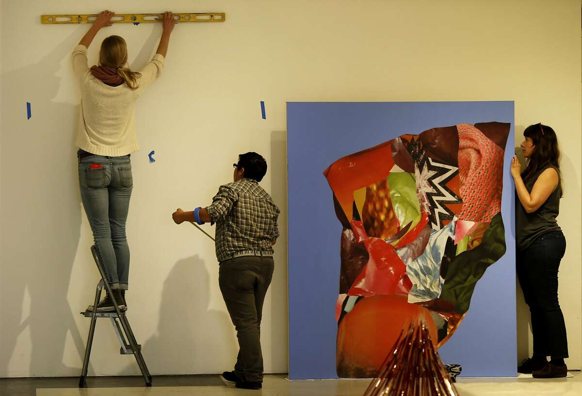Artists Cayla Harris (left), Susa Cortez and Holly Coley help hang a picture by Megan Reed for the upcoming MFA NOW exhibit Monday March 9, 2015 in San Francisco, Calif. A year after being gentrified out of the Mission District, the arts nonprofit Root Division is working out of a temporary space in the 1000 block of Market Street before moving to their new digs on Mission Street.