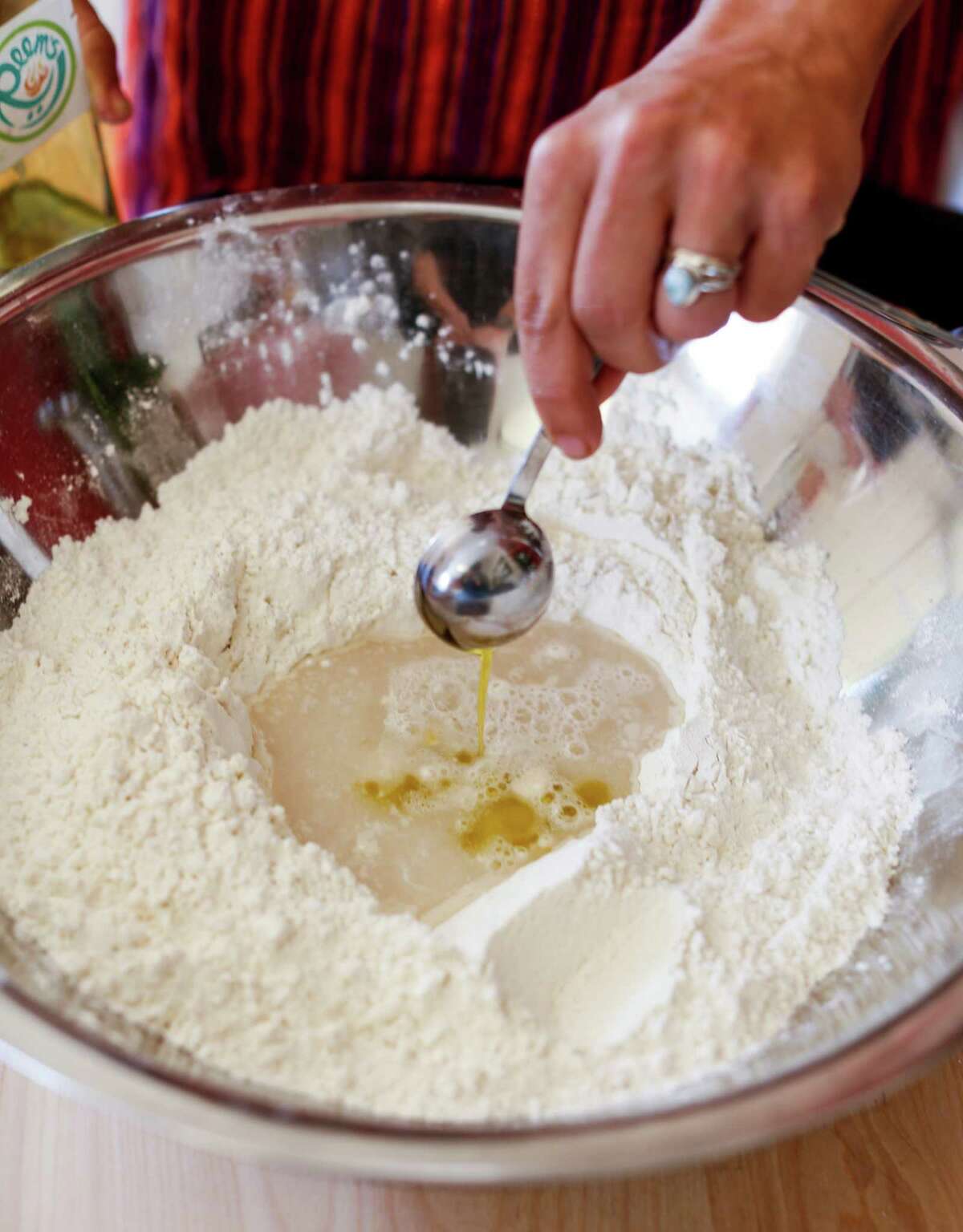 Reem Assil adds olive oil to a mixture of dry ingredients and water to make man’oushe, a Lebanese flatbread.