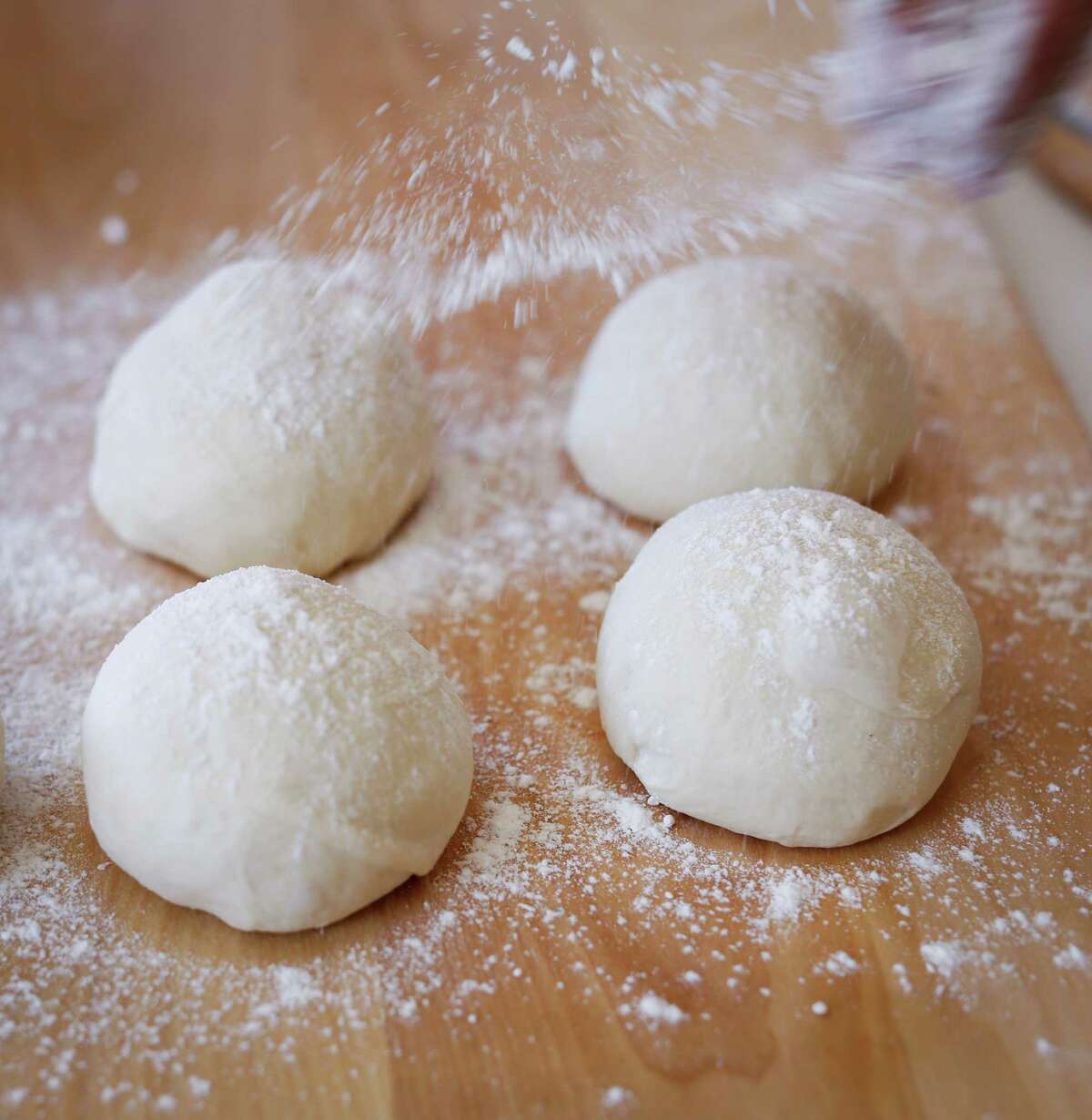 Reem Assil dusts balls of dough with flour for man’oushe in her Oakland kitchen.