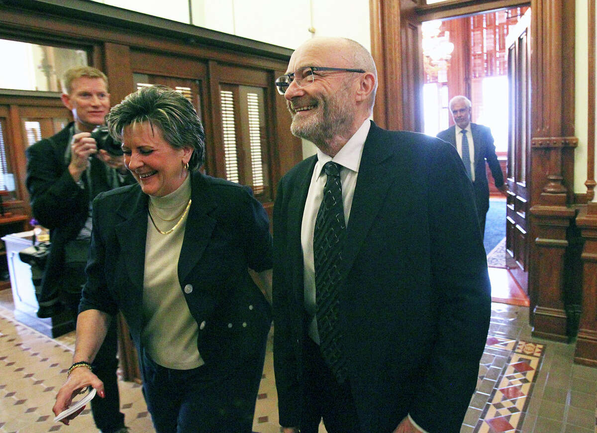 Phil Collins walks with Director of the Alamo Endowment Kaye Tucker onto the House floor to be recognized at the State Capitol as an honorary Texan on March 11, 2015.