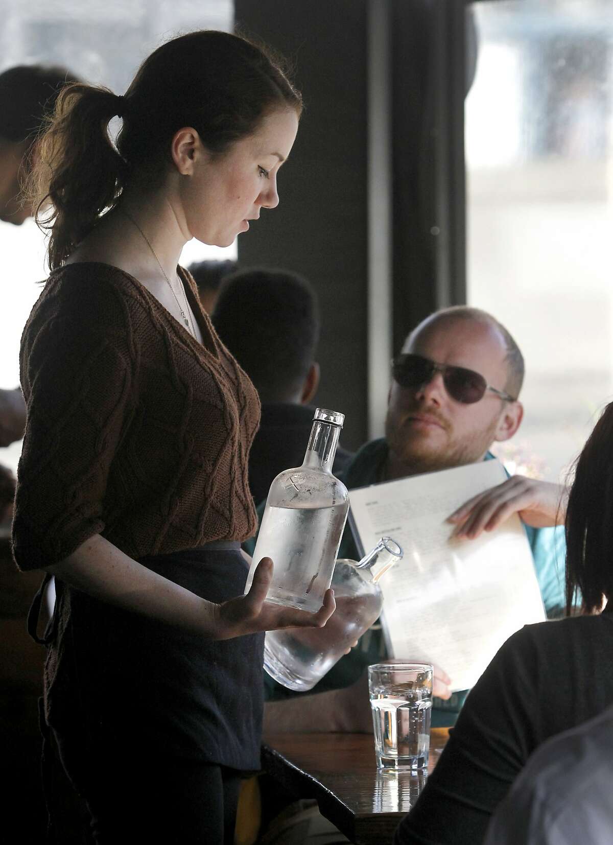 Greta Sanford serves water to Thomas Forss at The Corner Store restaurant in San Francisco, Calif. on Thursday, March 12, 2015. Proposed statewide conservation rules would require restaurants to ask customers if they would like water before serving it.